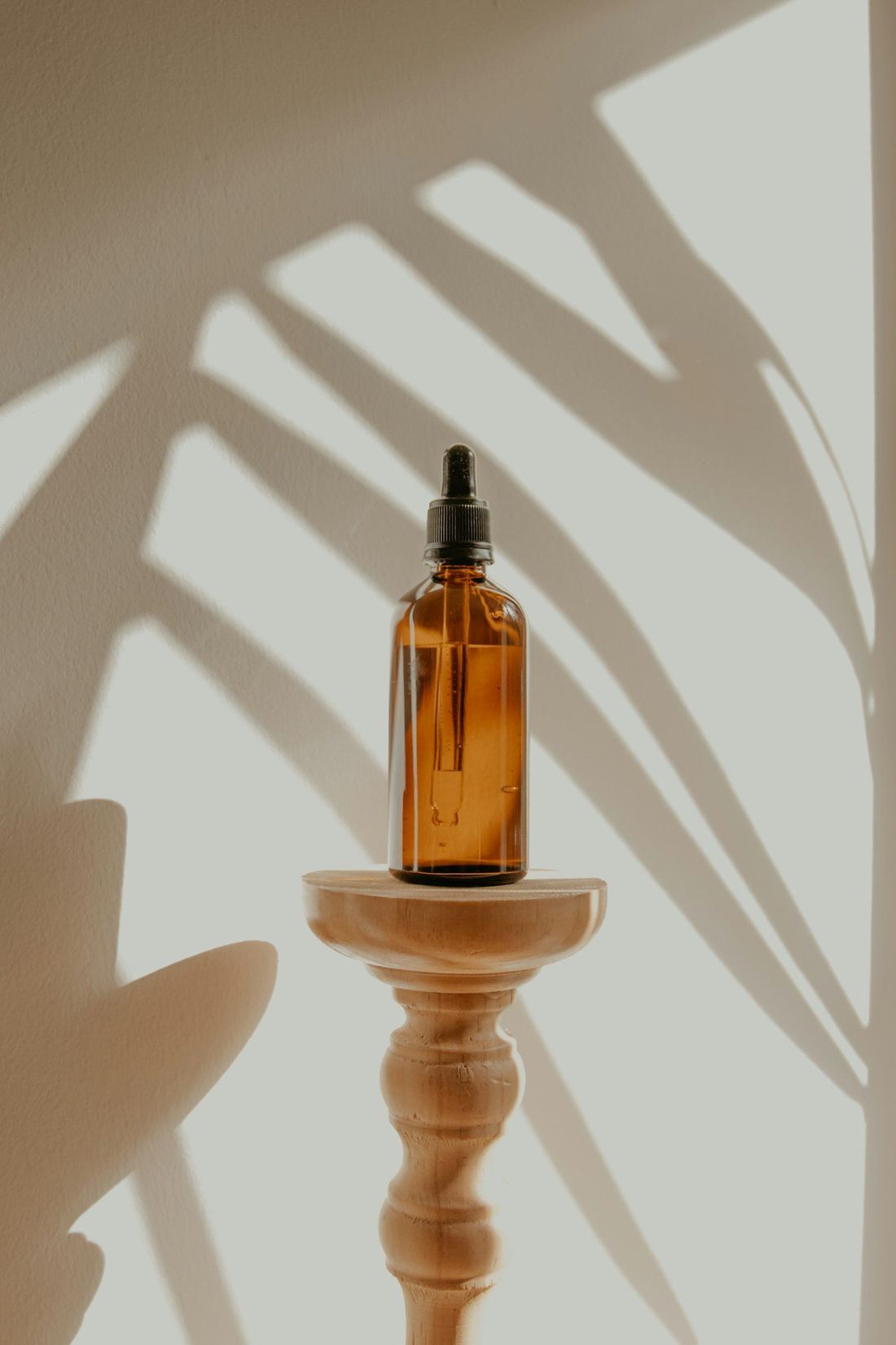 An amber glass dropper vial on a wooden stand in warm light